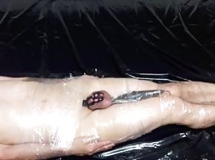 The mistress wraps the slave in plastic wrap and tortures him with vibrations on his full testicles