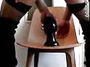 crossdresser sitting on a large buttplug 