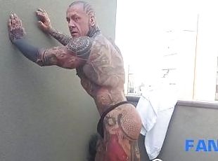 The legend of muscles and ink: Tattooed giant Rob Diesel, shows his power on the balcony